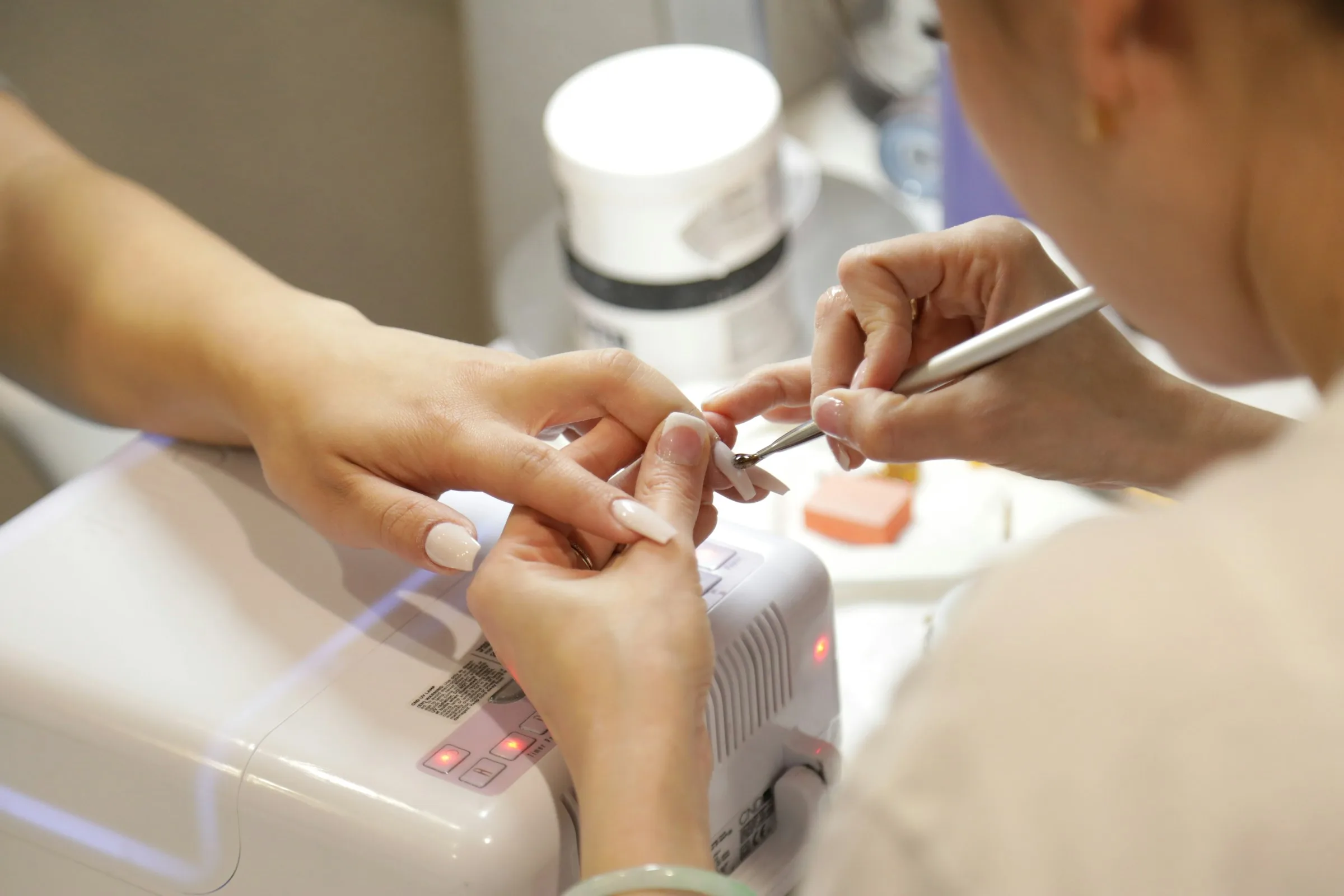 Una profesional aplicando esmalte semipermanente en una manicura, de cerca