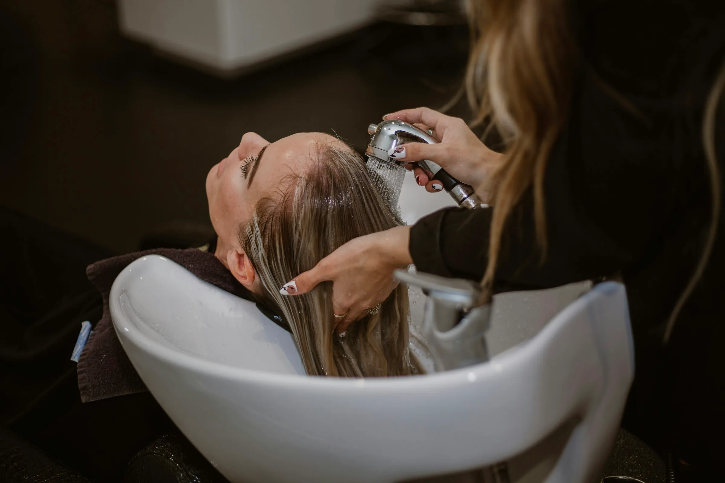 Una profesional lavando el cabello a una clienta en la peluquería, de cerca